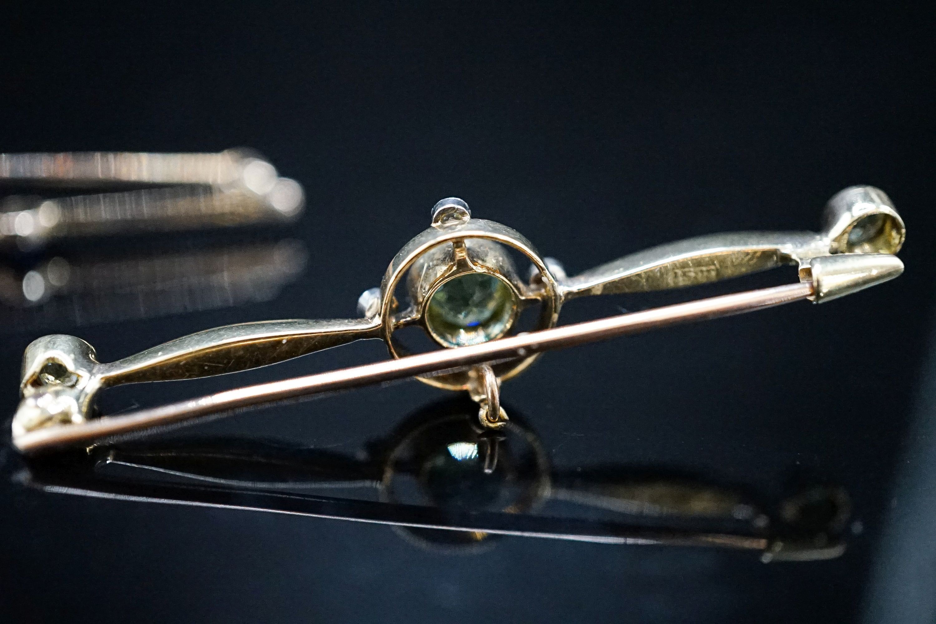 An Edwardian 15ct, peridot and diamond set bar brooch, 49mm, gross weight 4.4 grams and a yellow metal, sapphire and diamond set seven stone bar brooch, gross 3 grams
